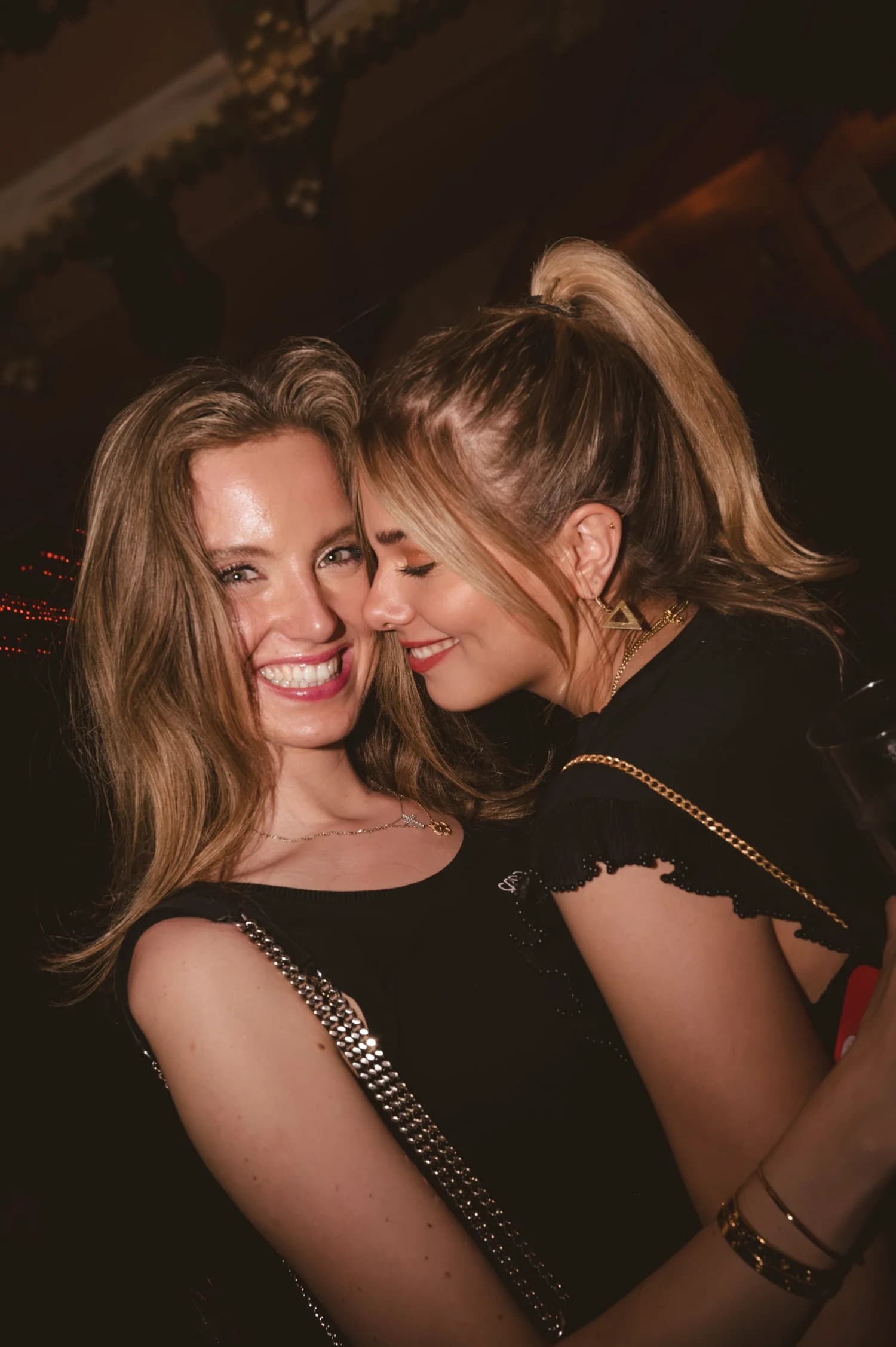 Two friends cheek to cheek, laughing on the rooftop