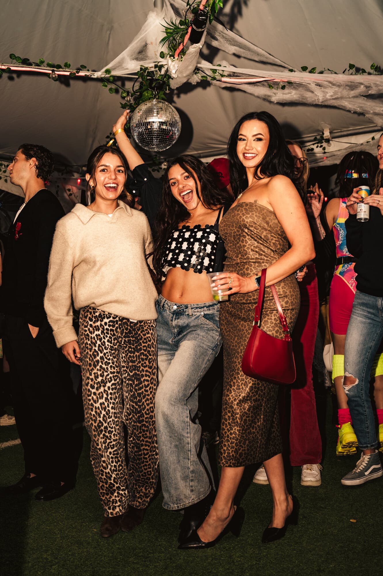 Four friends in Halloween costumes posing together under a disco ball