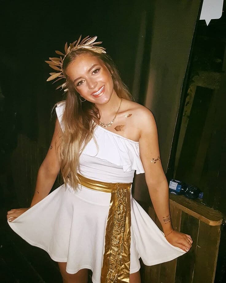 A woman in a Greek goddess costume smiling at the camera