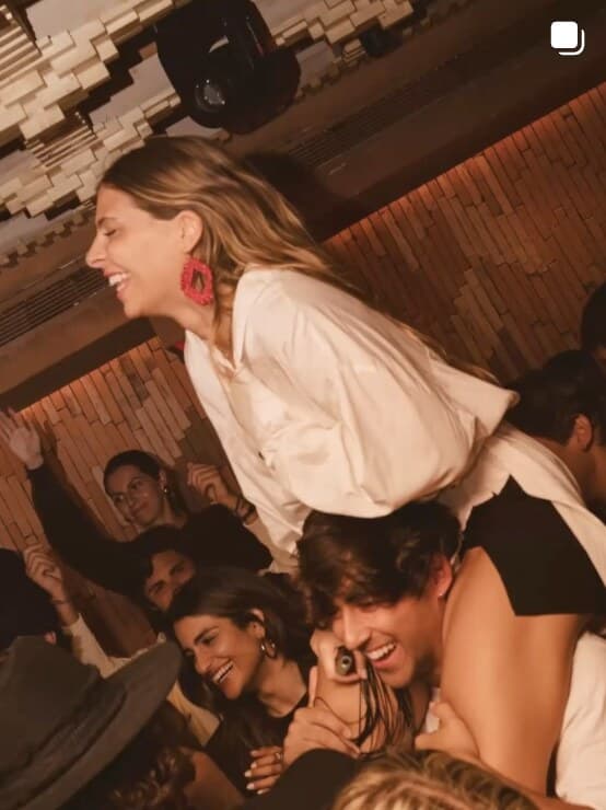 A woman laughing up on a friend's shoulders above the crowd